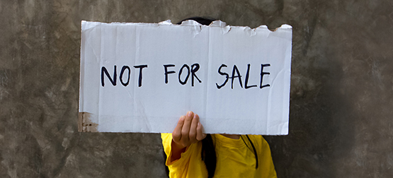 Child holding up a sign that says 'Not for sale'